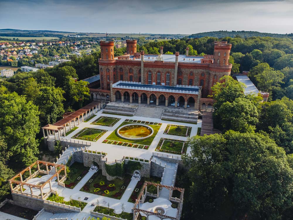 Pałac Marianny Orańskiej w otoczeniu rozległych ogrodów i zieleni, widok z lotu ptaka ukazujący symetryczny układ tarasów i fontann.