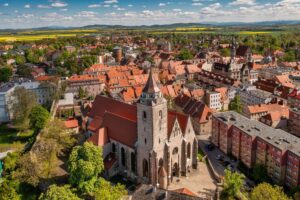 Ujęcie z lotu ptaka na kościół św. Marcina w Jaworze, otoczony gęstą zabudową starego miasta z czerwonymi dachami. W tle widać pola i wzgórza Dolnego Śląska.