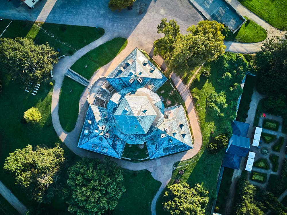 Widok z góry na Zamek Karlova Koruna w Chlumcu nad Cidliną, ukazujący jego gwiaździsty plan z centralną kopułą i symetrycznymi skrzydłami otoczonymi zielenią.