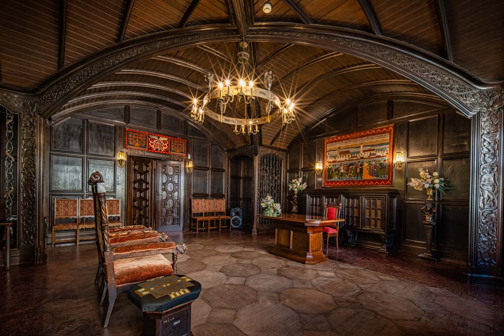Reprezentacyjna sala Ratusza w Lwówku Śląskim z ciemną, drewnianą boazerią i sklepionym sufitem. Pośrodku stoi stół i krzesła, a całość oświetla duży żyrandol.