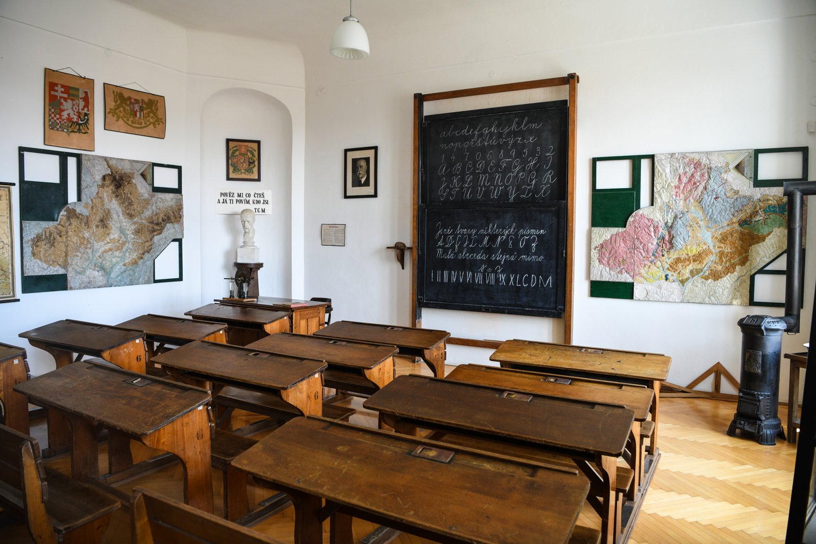 Sala szkolna w Muzeum Jana Amosa Komenského w Přerovie z drewnianymi ławkami, tablicą, mapami i popiersiem pedagoga.