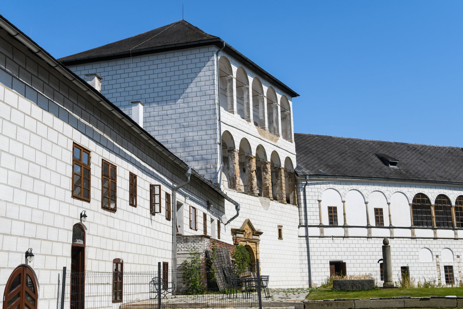 Fasada renesansowego pałacu Kolštejn – arkadowe loggie, białe mury i historyczne detale architektoniczne na tle błękitnego nieba.