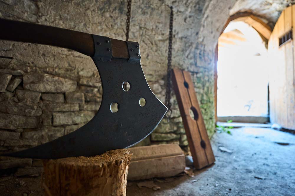 Zamek Vizmburk – zbliżenie na replikę topora katowskiego w kamiennej komnacie, element wystawy o średniowiecznych narzędziach.