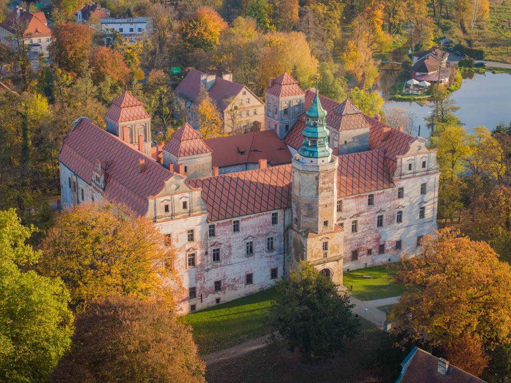 Zamek Niemodlin z lotu ptaka jesienią – monumentalna rezydencja pośród barwnych drzew i stawów południowej Opolszczyzny.