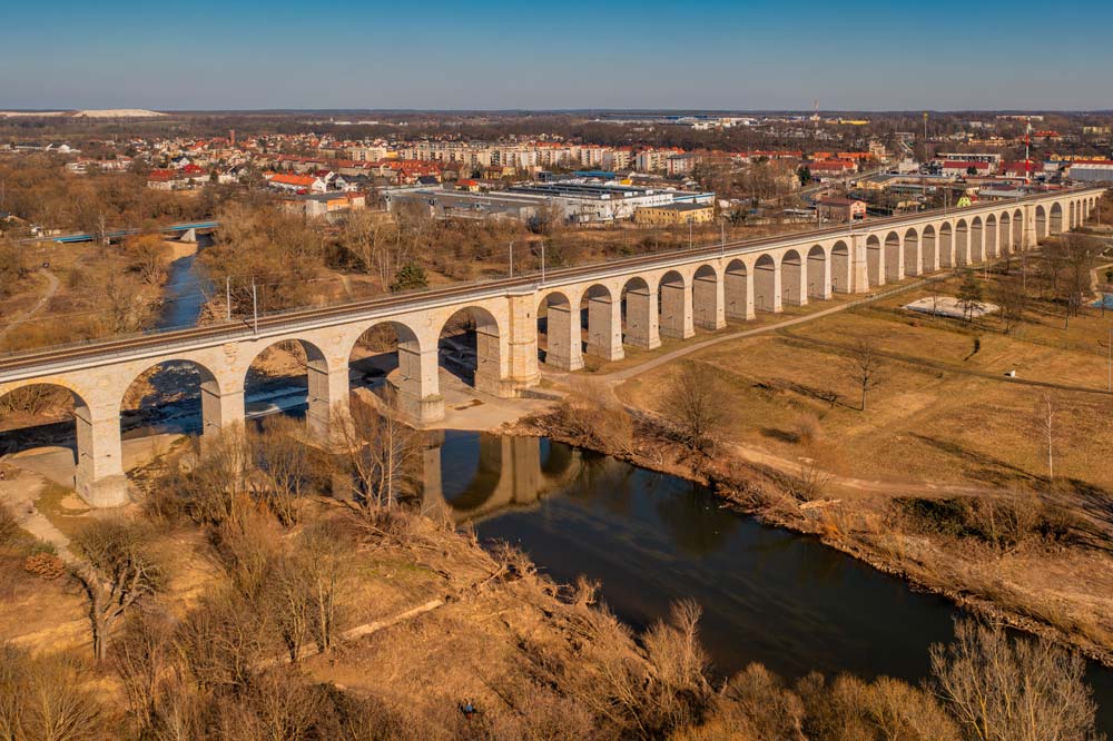 Wiadukt kolejowy w Bolesławcu z lotu ptaka – długi ciąg kamiennych łuków nad doliną Bobru i zabudową miasta.