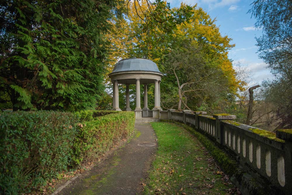 Parkowa ścieżka prowadząca do okrągłej altany (glorietty) na kolumnach, otoczonej zielenią i starodrzewem w Rogowie Opolskim.