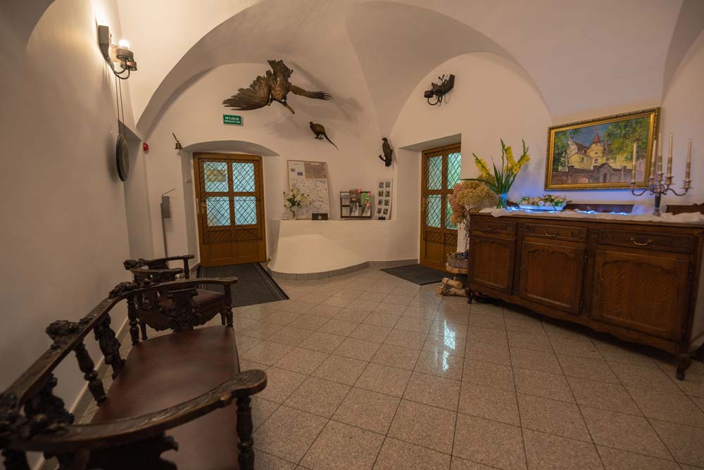 Długa, sklepiona sala z dużym stołem i drewnianą boazerią; na ścianach motywy myśliwskie i poroże – wnętrze zamku w Rogowie Opolskim.