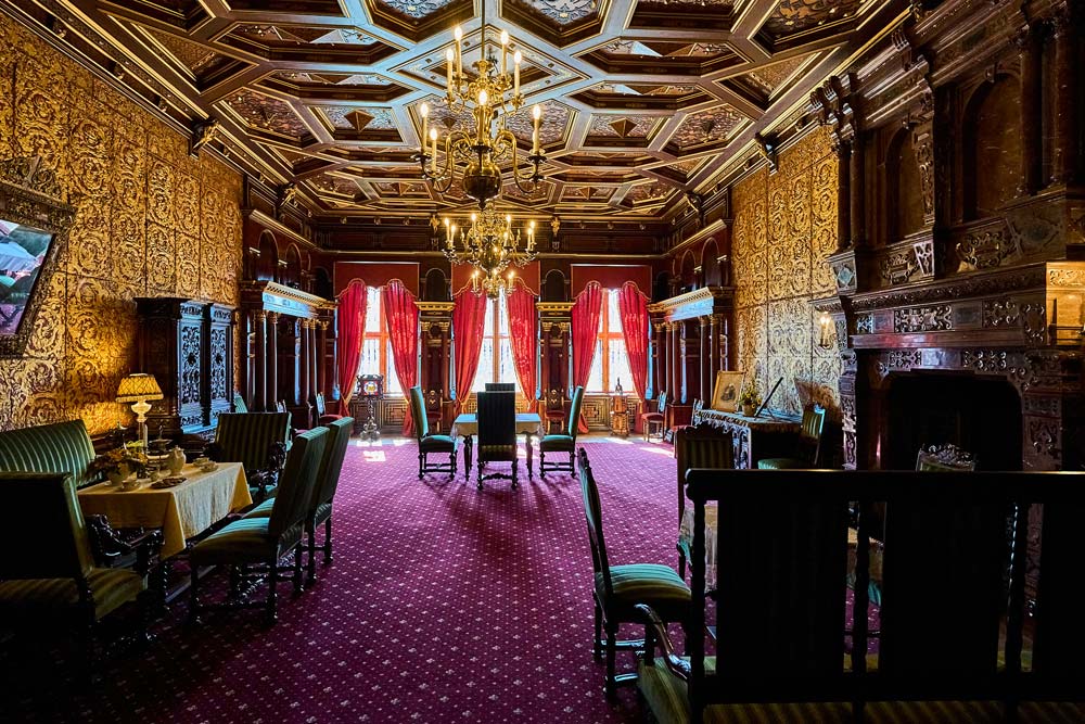 Reprezentacyjna sala w Hradec u Nechanic: bogato zdobione ściany, żyrandole i czerwone zasłony przy wysokich oknach.