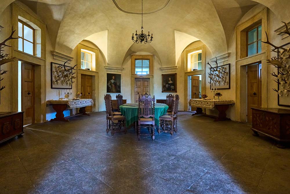 Sala z kolekcją myśliwską w Humprechcie: sklepione wnętrze, okrągły stół i poroża na ścianach.