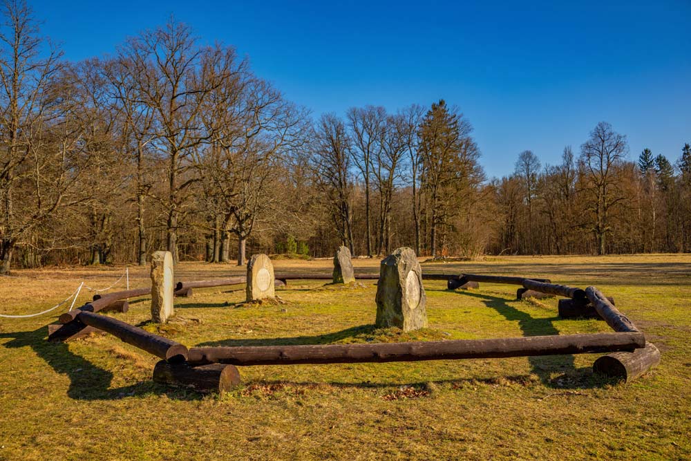 Cmentarz koni w Kliczkowie z trzema kamiennymi nagrobkami na tle starych drzew