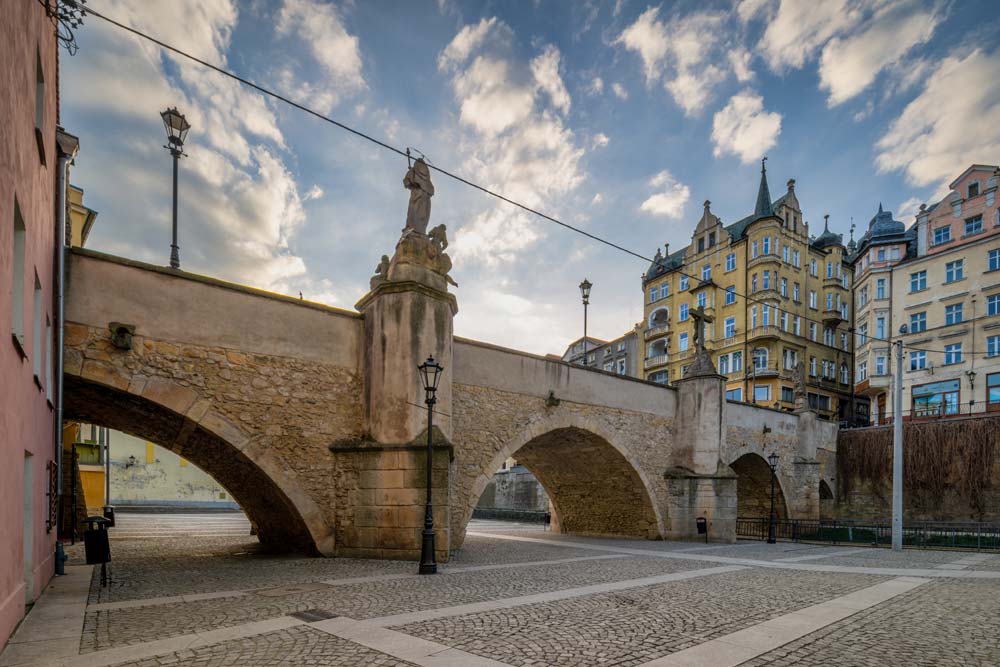 Kamienny Most Św. Jana w Kłodzku i barokowe figury świętych na tle kościoła oraz starówki