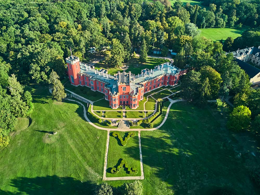 Ujęcie dronem: Hradec u Nechanic na tle zielonego parku, z ozdobnymi parterami przed fasadą.