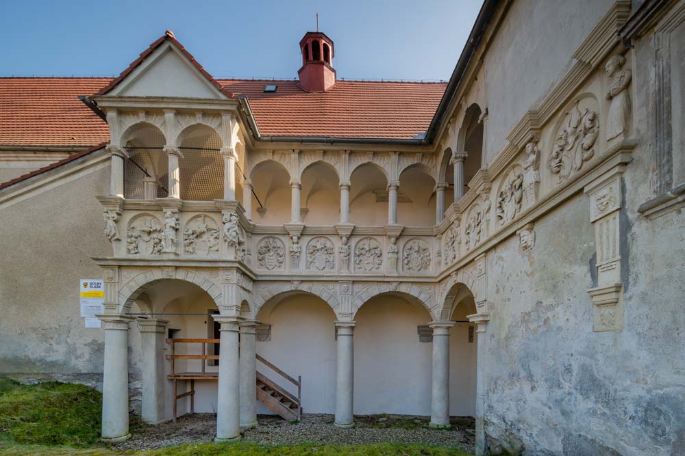 Narożnik dwukondygnacyjnych renesansowych krużganków w Nawojowie Łużyckim z kolumnami toskańskimi i jońskimi oraz rzeźbionym fryzem heraldycznym