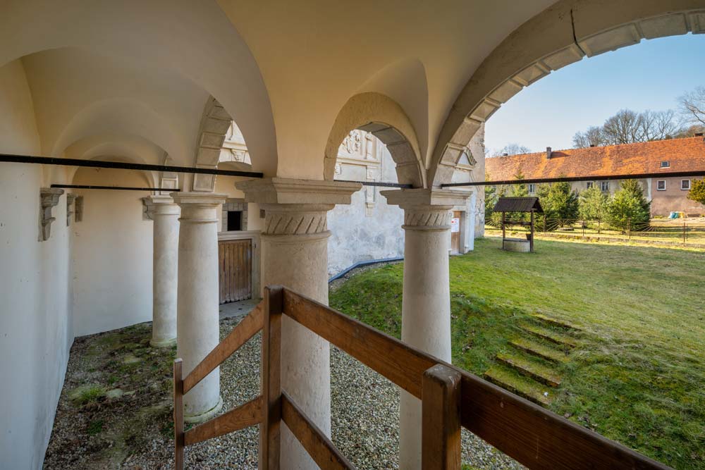 Widok spod arkad renesansowej loggii w Nawojowie Łużyckim na dziedziniec i zabudowania gospodarcze