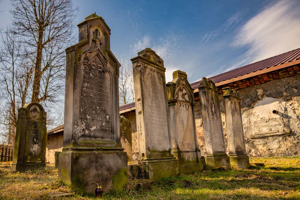 Hebrajskie inskrypcje na macewach kirkutu w Kamiennej Górze, u podstawy czerwony znicz