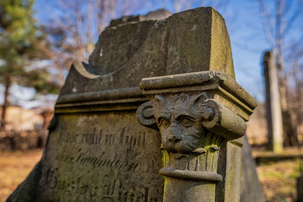 Głowica z rzeźbioną maską lwa nad niemiecką inskrypcją kupca na macewie w Kamiennej Górze